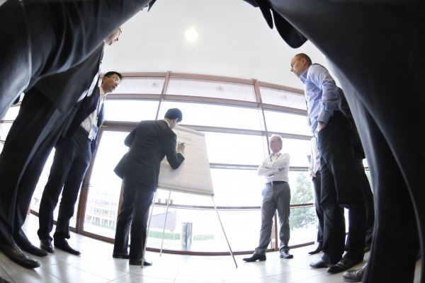 Company Assessment - Bee-Best: a group of men discuss and take notes around a flipchart